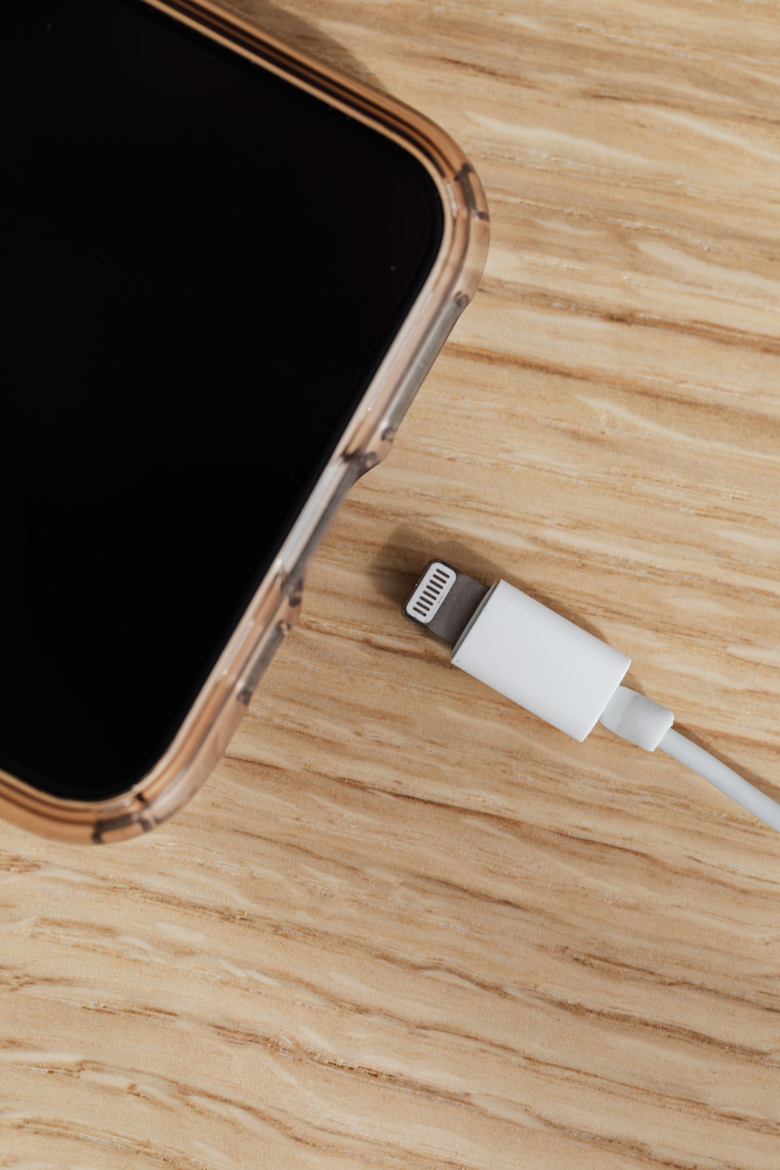 Smartphone and charger on a wooden table