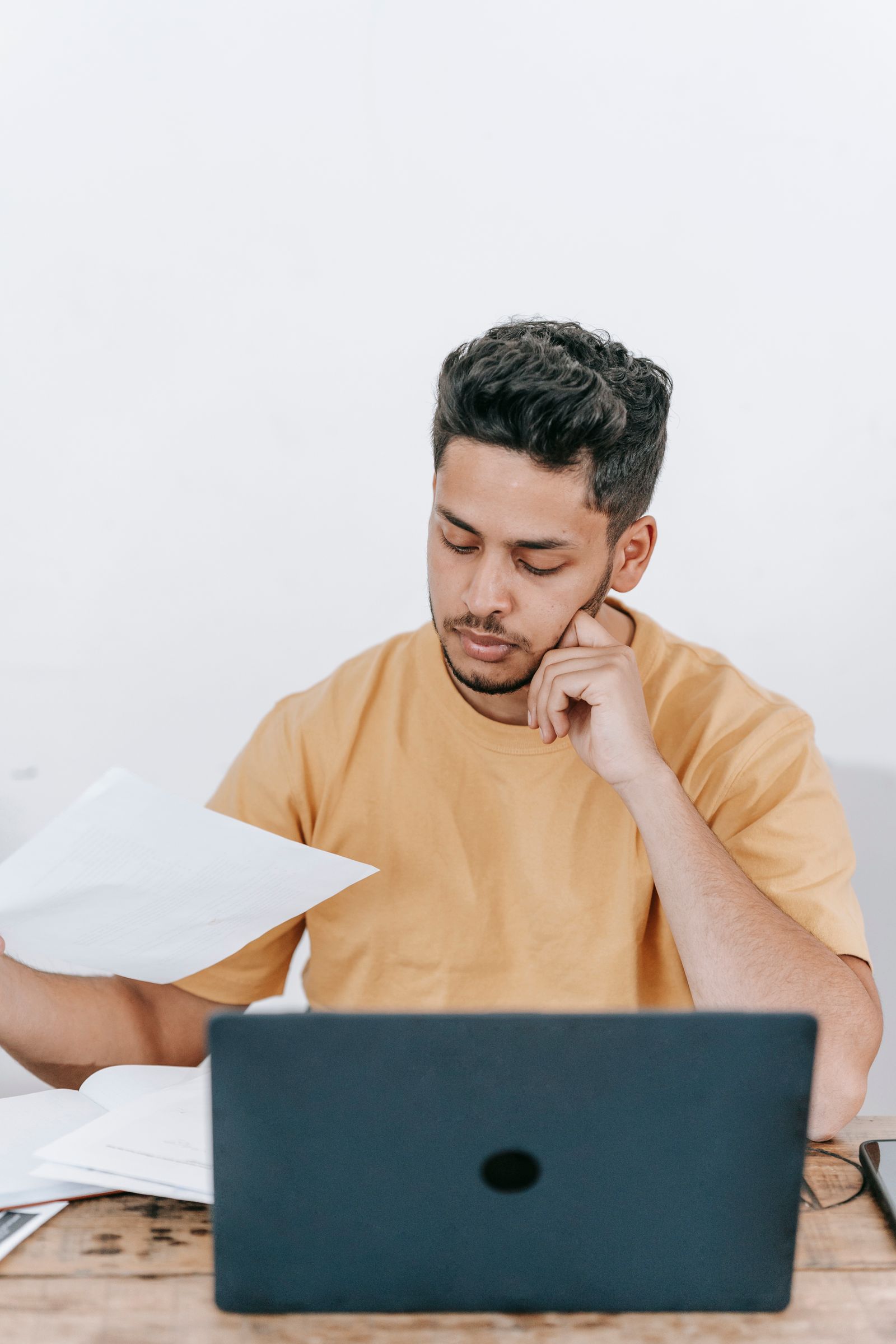Man organising documents with a laptop