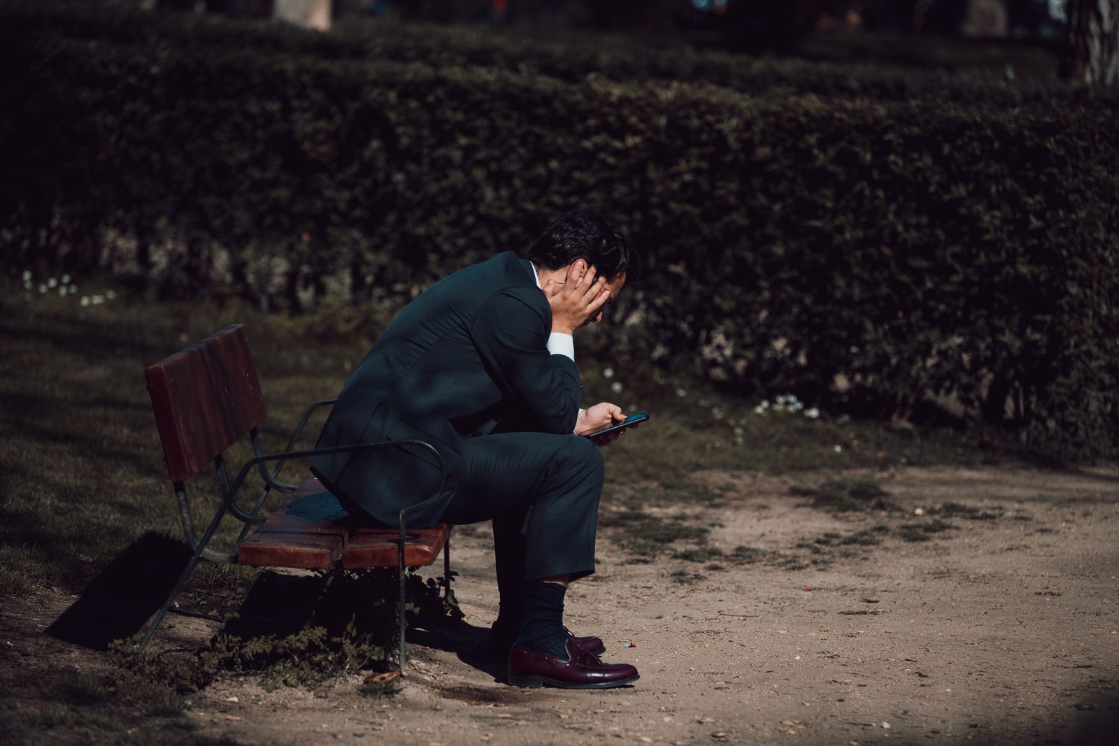A worried man holding his phone outdoors