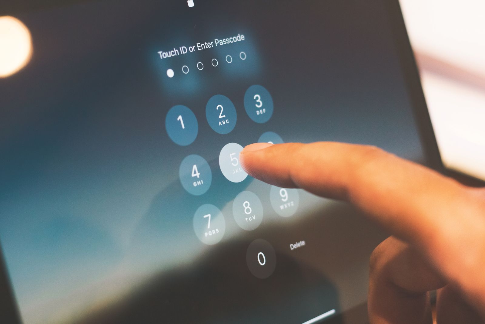 Finger entering a passcode on a phone security screen