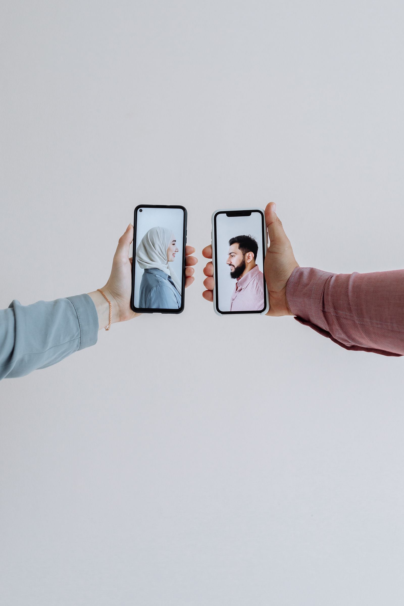 Two hands holding phones face to face