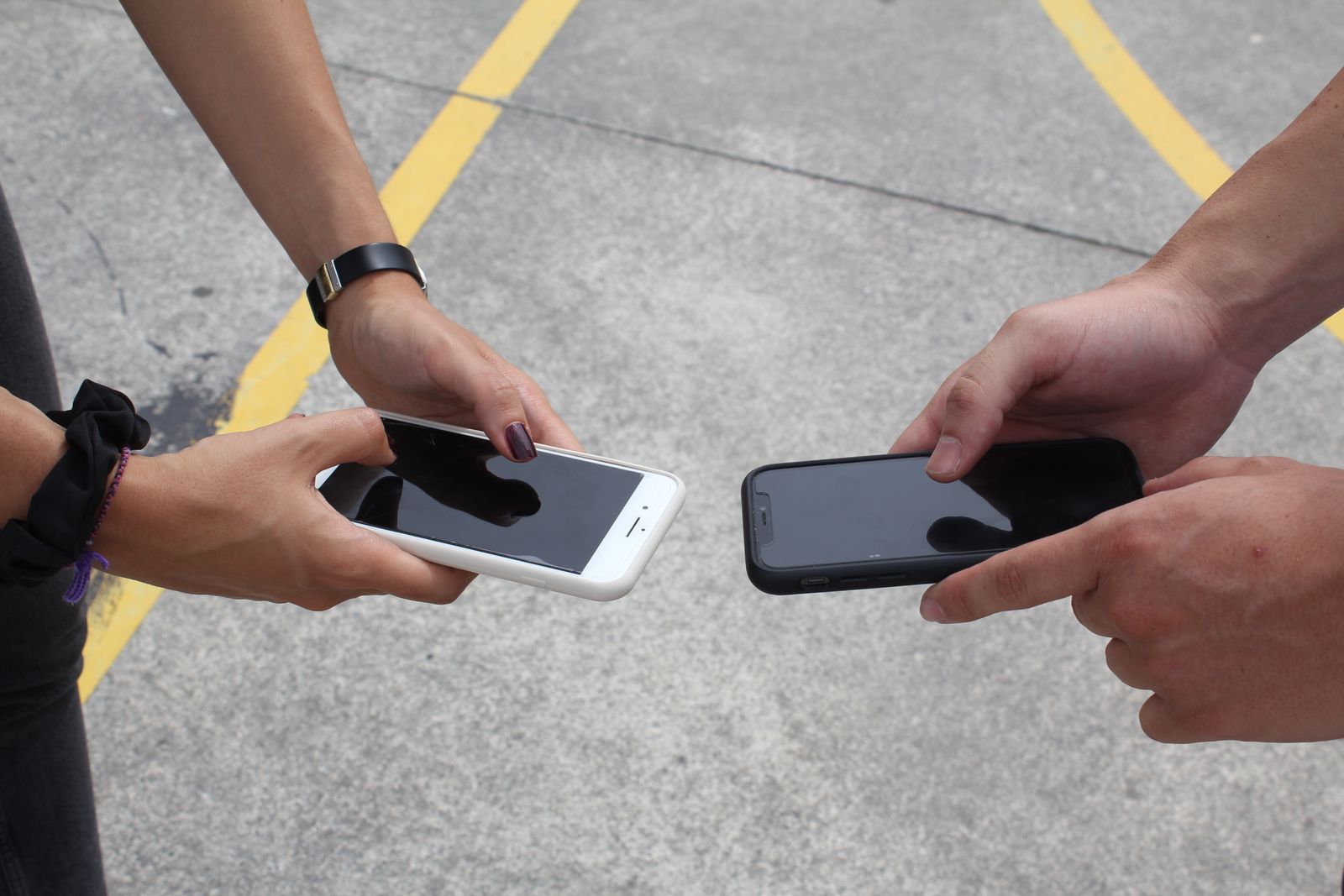 Hands holding smartphones outdoors